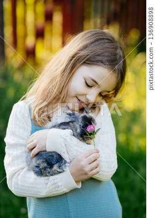 Young girl gently cuddles a fluffy bunny in her arms. Young girl gently cuddles a fluffy bunny in her arms. 136908898
