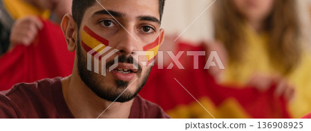 Excited football fans supporting spanish national team in live soccer match at stadium. 136908925
