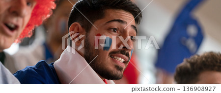 Excited football fans supproting French national team in live soccer match at stadium. Excited football fans supproting French national team in live soccer match at stadium. 136908927