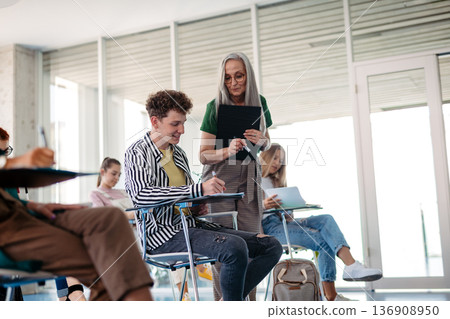 Group of college students attending lecture in university hall. Group of college students attending lecture in university hall. 136908950