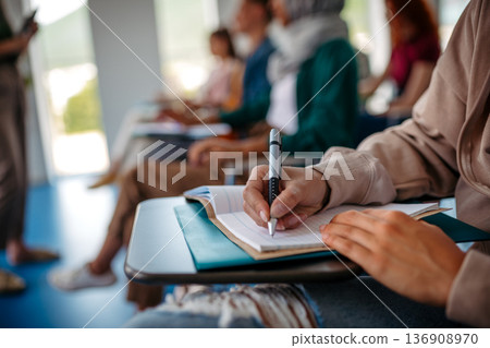 Close up of college student writing notes during lecture. 136908970