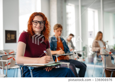 Group of college students attending lecture in university hall. 136908976