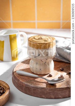 Dalgona coffee on a kitchen orange tile background with coffee beans, milk jug and morning shadows. 136909535
