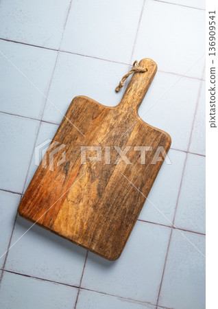 Empty wooden cutting board on a kitchen tile background with natural light. 136909541