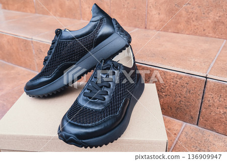 Elegant black leather womens shoes blank product for branding displayed on recycled cardboard box. New casual female sneakers no-brand footwear e-commerce. No logo product Elegant black leather womens shoes blank product for branding displayed on recycled cardboard box. New casual female sneakers no-brand footwear e-commerce. No logo product 136909947