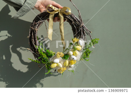 Woman hand Handmade Easter wreath made of sustainable materials decorations in yellow color. Homemade decor Easter celebration gift present ideas. Copy space Woman hand Handmade Easter wreath made of sustainable materials decorations in yellow color. Homemade decor Easter celebration gift present ideas. Copy space 136909971