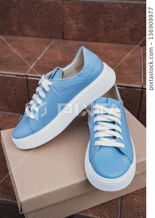 Elegant blue leather womens shoes blank product for branding displayed on recycled cardboard box. New casual female sneakers no-brand footwear e-commerce. No logo product unbranded fashion Elegant blue leather womens shoes blank product for branding displayed on recycled cardboard box. New casual female sneakers no-brand footwear e-commerce. No logo product unbranded fashion 136909977