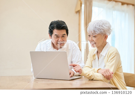 Senior Asian couple using a PC in the living room 136910120