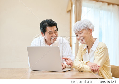 一對年長的亞裔夫婦在客廳使用電腦 136910121