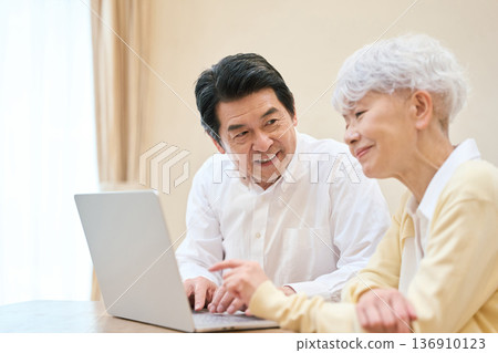 Senior Asian couple using a PC in the living room Senior Asian couple using a PC in the living room 136910123
