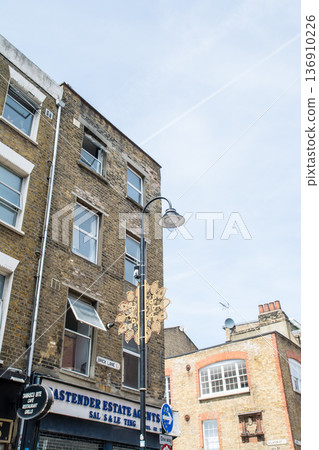 A street lined with historic brick buildings under bright sunlight in Shoreditch, East London 136910226