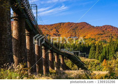一列火車駛過磚砌的木戶澤橋，背景是秋天的樹葉（JR上越線） 136910266
