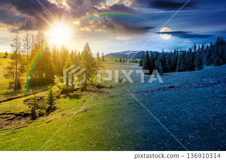 mountain landscape during spring. day meet night. sun and moon over peaceful countryside scenery with coniferous forest near grassy field. beautiful ridge with snow capped top in the distance mountain landscape during spring. day meet night. sun and moon over peaceful countryside scenery with coniferous forest near grassy field. beautiful ridge with snow capped top in the distance 136910314