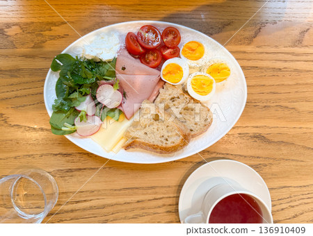 Top view breakfast plate with tea and fresh ingredients on wooden table. Homemade brunch, balanced diet, protein nutrition, and cafe atmosphere concept. 136910409