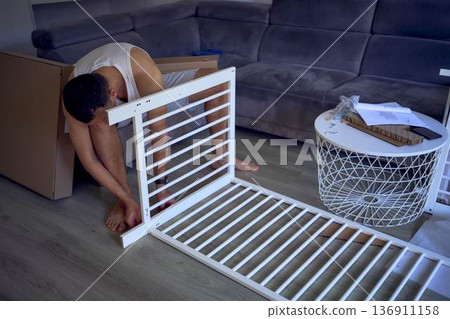 New dad to be building a cradle for his newborn in a bright simple room New dad to be building a cradle for his newborn in a bright simple room 136911158