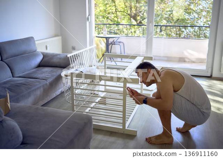 New dad to be building a cradle for his newborn in a bright simple room New dad to be building a cradle for his newborn in a bright simple room 136911160