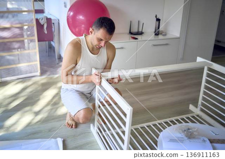 New dad to be building a cradle for his newborn in a bright simple room 136911163