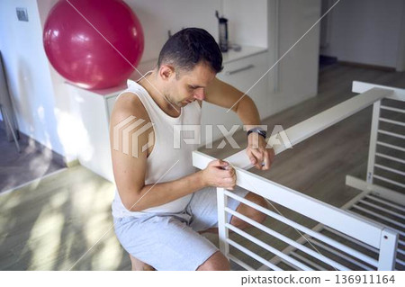 Expectant father preparing a nursery by assembling a wooden crib Expectant father preparing a nursery by assembling a wooden crib 136911164