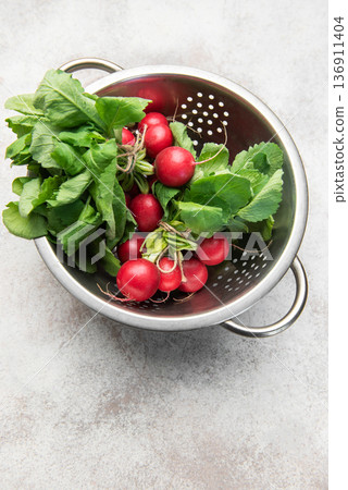 Fresh radishes with green tops in colander Fresh radishes with green tops in colander 136911404