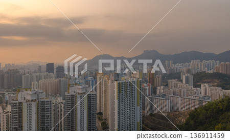 Hazy Kowloon skyline glowing under warm sunset Feb 19 2026 136911459