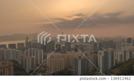 Hazy Kowloon skyline glowing under warm sunset Feb 19 2026 136911462