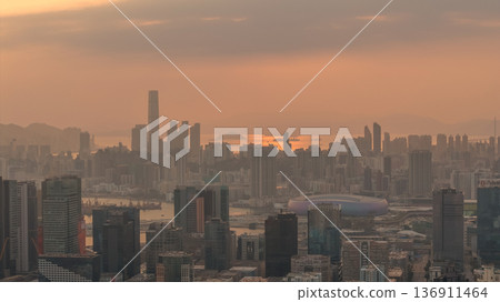 Hazy Kowloon skyline glowing under warm sunset Feb 19 2026 136911464