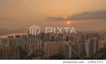 Hazy Kowloon skyline glowing under warm sunset Feb 19 2026 136911471