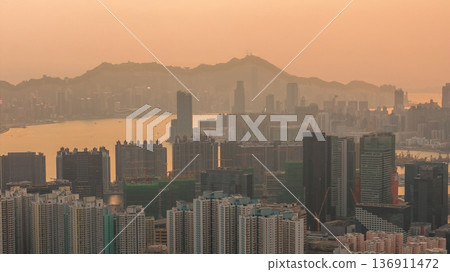 Hazy Kowloon skyline glowing under warm sunset Feb 19 2026 136911472