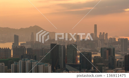 Hazy Kowloon skyline glowing under warm sunset Feb 19 2026 136911475