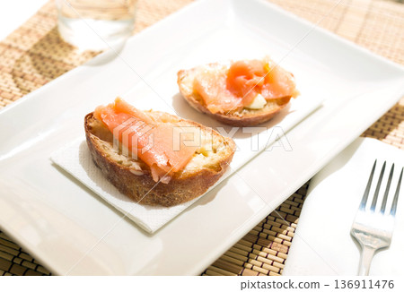 Delicious canapes of salted smoked salmon fillet on a slice of fresh ciabatta on the table 136911476