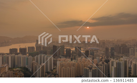 Hazy Kowloon skyline glowing under warm sunset Feb 19 2026 136911485