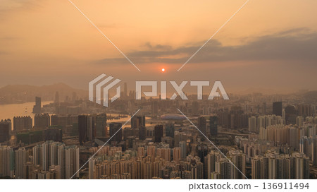 Hazy Kowloon skyline glowing under warm sunset Feb 19 2026 136911494