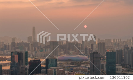 Hazy Kowloon skyline glowing under warm sunset Feb 19 2026 136911502
