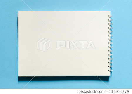 Blank spiral sketchbook on a bright blue background - top view Blank spiral sketchbook on a bright blue background - top view 136911779