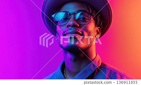 Young man with stylish glasses and hat poses against a vibrant purple and pink backdrop in a contemporary setting 136911855