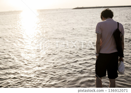 Man walking on the beach at sunset Man walking on the beach at sunset 136912071