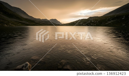 Alpine lake with rain ripples at golden hour as a storm clears from a ridge line 136912423