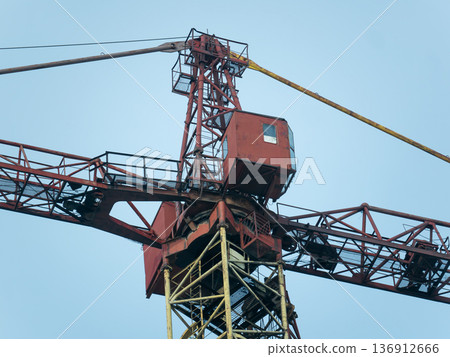 Industrial construction crane against a clear blue sky. Heavy machinery for building and development project. Lifting equipment. Industrial construction crane against a clear blue sky. Heavy machinery for building and development project. Lifting equipment. 136912666