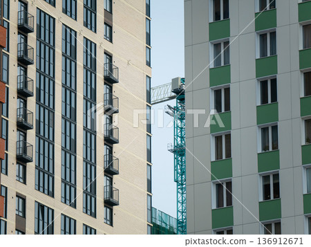 New residential buildings with construction crane in between. Modern urban development and progress in city architecture design. 136912671