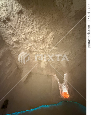 Salt cave ceiling with textured mineral formations and warm backlight. Natural therapy environment, breathing wellness and calming interior atmosphere Salt cave ceiling with textured mineral formations and warm backlight. Natural therapy environment, breathing wellness and calming interior atmosphere 136912728