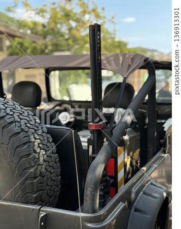 Off-road vehicle with spare tire and open-top design parked outdoors under clear sky Off-road vehicle with spare tire and open-top design parked outdoors under clear sky 136913301