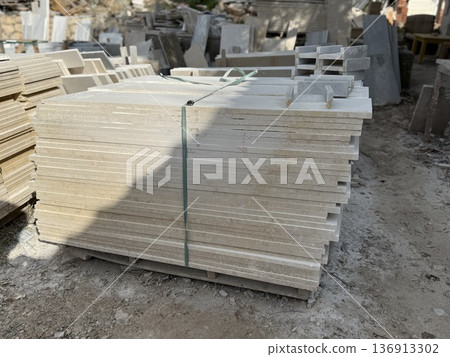 Stack of stone slabs in outdoor workshop with scattered rubble and construction materials 136913302