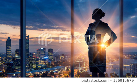 一位商務人士的剪影矗立在美麗的夜景城市背景下。多次曝光和耀眼的光線與城市景觀交相輝映。 136913679
