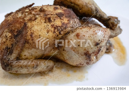Whole roasted chicken with crispy skin resting on a white plate, prepared delicious poultry meal for dinner or Thanksgiving. Whole roasted chicken with crispy skin resting on a white plate, prepared delicious poultry meal for dinner or Thanksgiving. 136913984