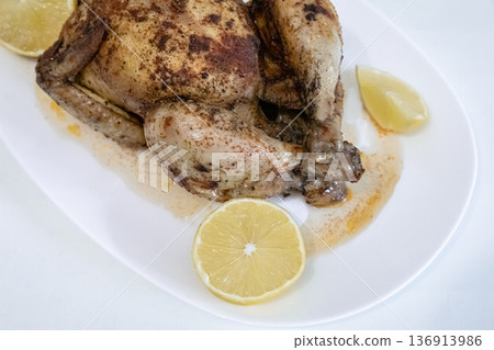 Roasted spiced chicken with lemon slices on a white plate. Homemade comfort food. Delicious meal for dinner or lunch. 136913986