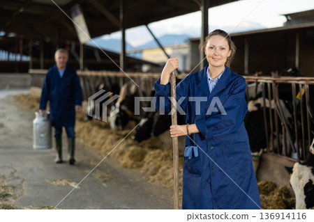 Successful woman farmer standing in cowshed at dairy cow farm 136914116