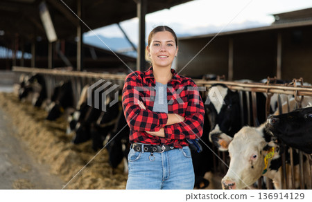 Portrait of cheerful girl farmer in cowhouse Portrait of cheerful girl farmer in cowhouse 136914129