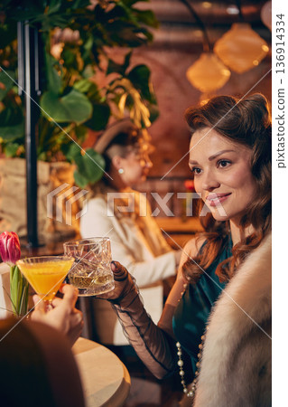 Stylish woman in fur stole clinking cocktail glass in vintage bar. Stylish woman in fur stole clinking cocktail glass in vintage bar. 136914334