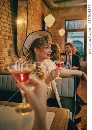 Elegant retro woman holding red cocktail in cozy brick bar. 136914363