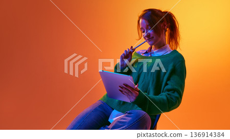 Smiling woman reviewing content on tablet device in modern studio lighting. Smiling woman reviewing content on tablet device in modern studio lighting. 136914384